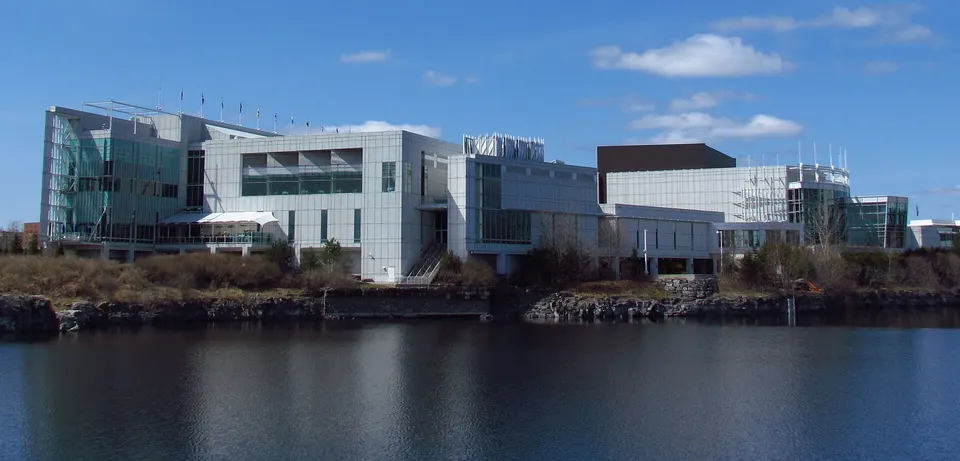 Le Casino du Lac-Leamy, grand bâtiment blanc aux façades vitrées, vu de l’autre côté du lac de la Carrière par une journée claire de printemps.